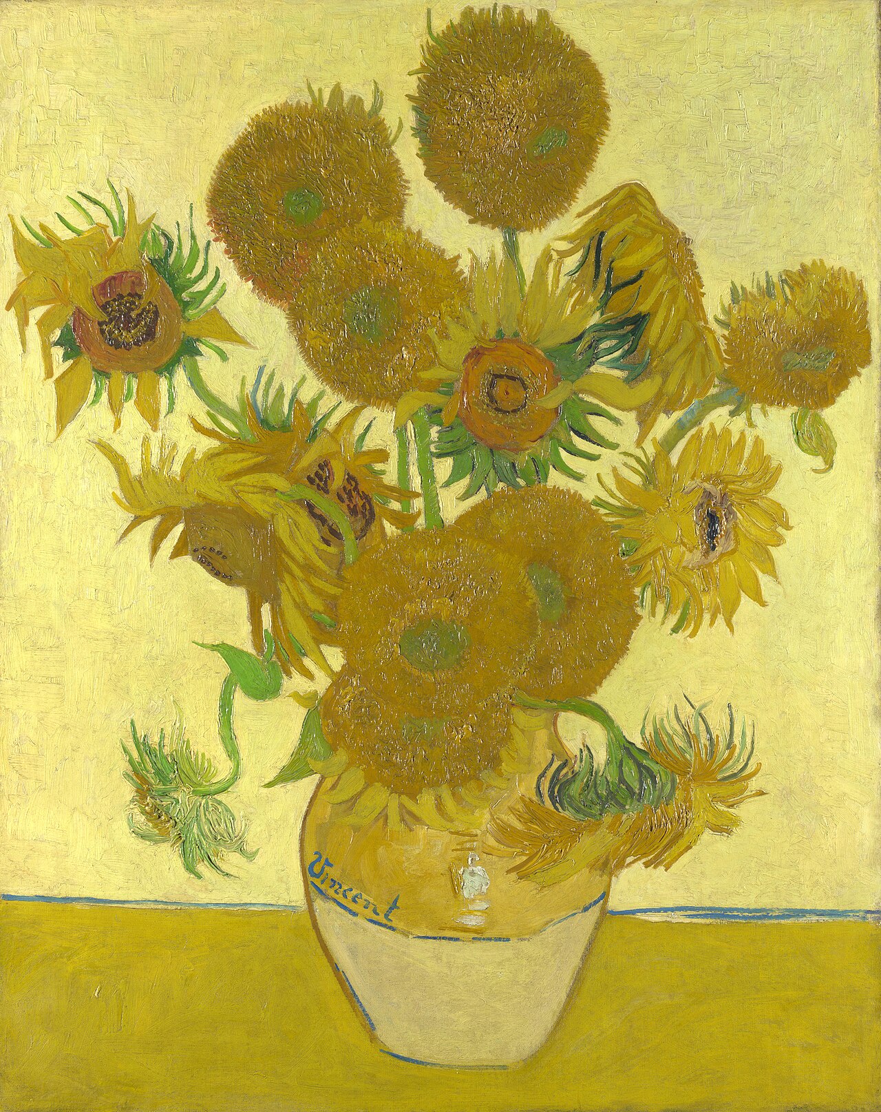Fifteen sunflowers crowded into a plain earthenware vase on a table, painted almost entirely in yellows &mdash; the wall behind, the table, the vase and the flowers all shades of the same colour. Some heads are in full flower, some have gone to seed and turned brown, and several are bent or facing away.